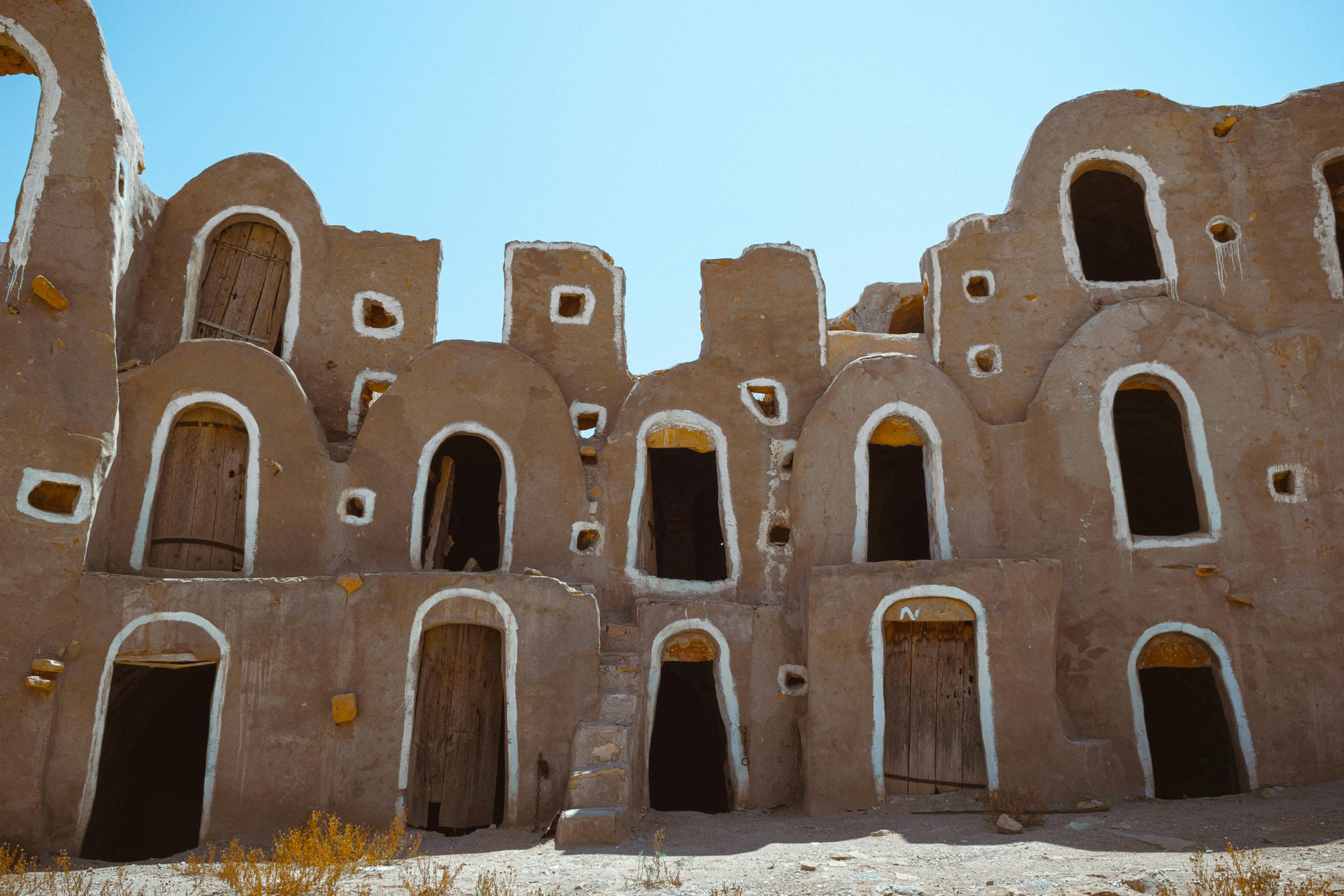 A three-storey mud palace with white highlights on its doors and windows representing ancient building practices used in the Modern World.