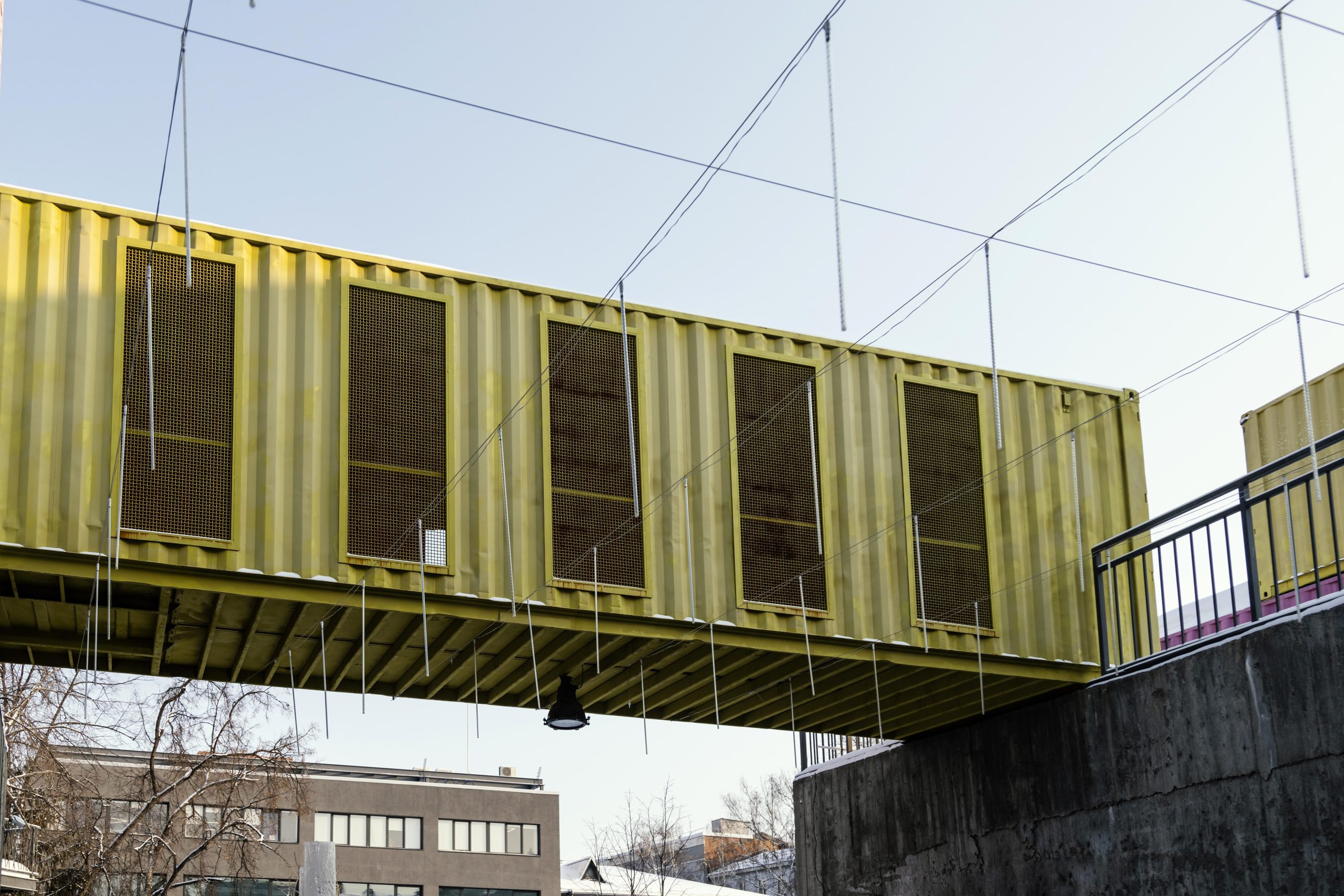 Shipping container bridge A yellow shipping container bridge with four openings on the side, portraying one of the 5 construction projects built using repurposed materials